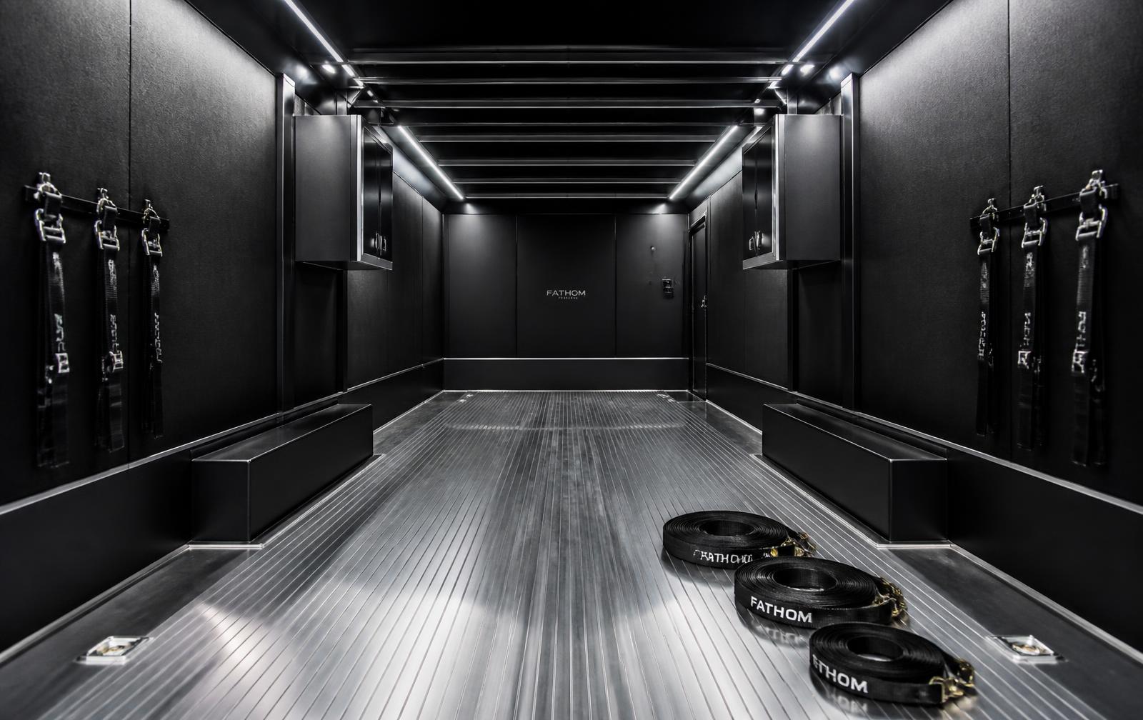 Interior of a clean enclosed car trailer with soft lighting and coiled straps